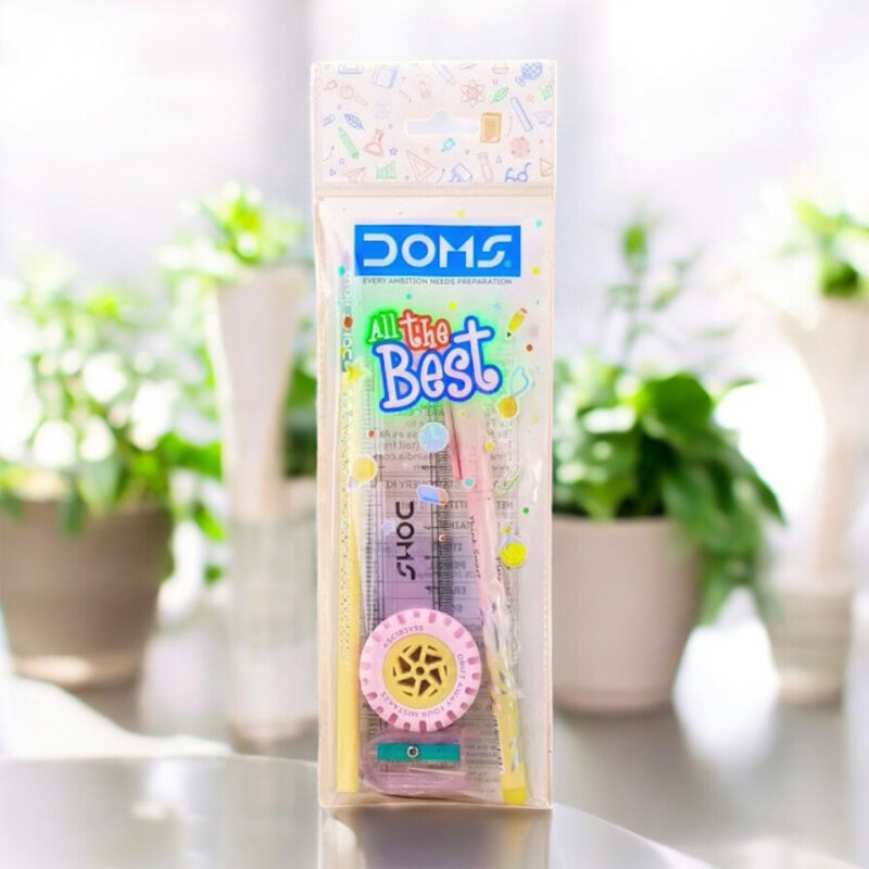 A single Doms All the Best Kit, showing a clear plastic pouch containing Doms brand stationery items like pencils, a ruler, an eraser, and a sharpener, with green plants in the background.