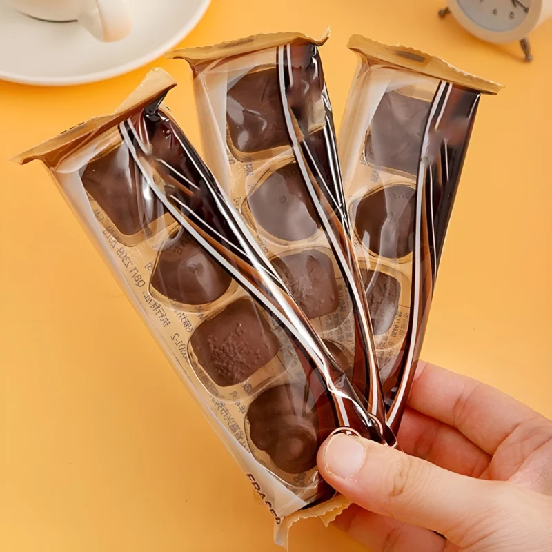 Three Chocolate Eraser Packs held in a hand, showing the individual chocolate-shaped erasers inside their clear plastic packaging.
