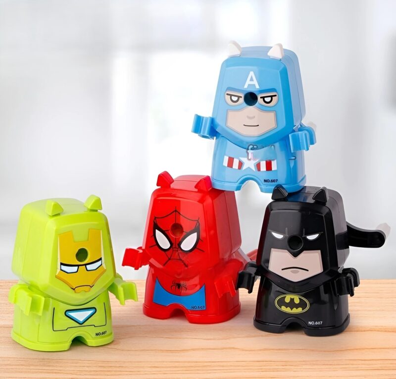 A group of four Avengers Manual Sharpeners in various superhero designs (Captain America, Spider-Man, Iron Man/Hulkbuster-like, and Batman) stacked and arranged on a wooden surface.