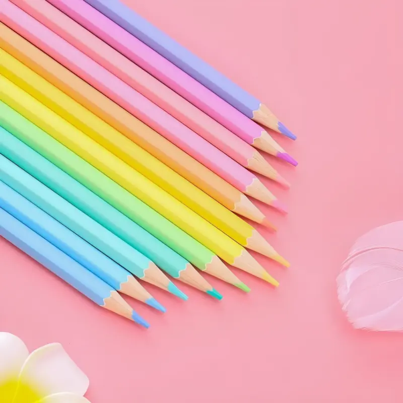 A full set of 12 sharpened Pastel Color Pencils arranged in a rainbow gradient line on a pink background, showcasing the soft color palette.
