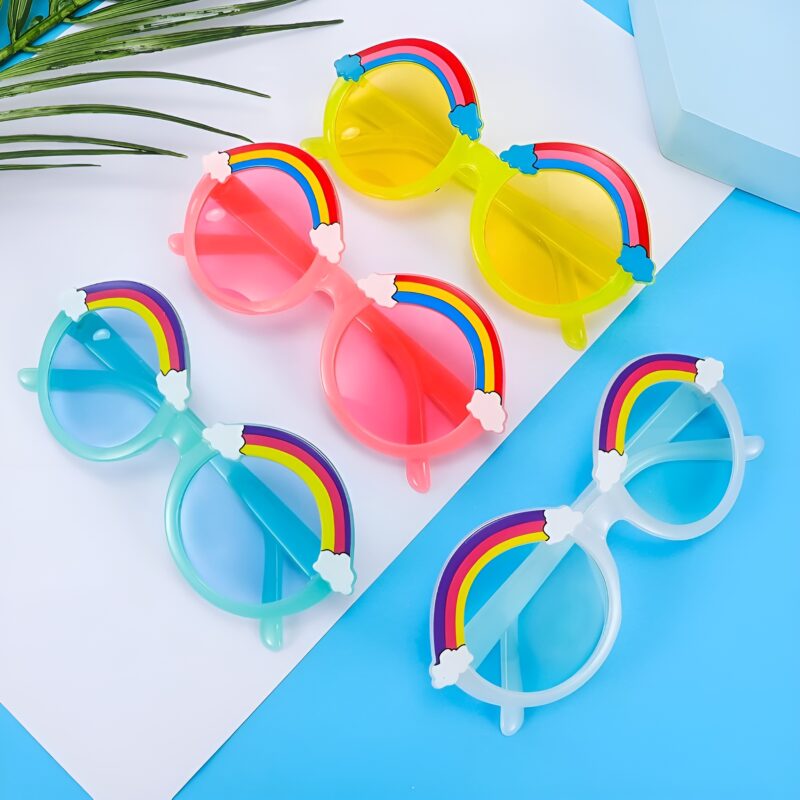 A display of six pairs of Dazzling Kids Rainbow Sunglasses with various colored frames (yellow, pink, blue, clear) and rainbow/cloud tops, arranged on a blue and white background.