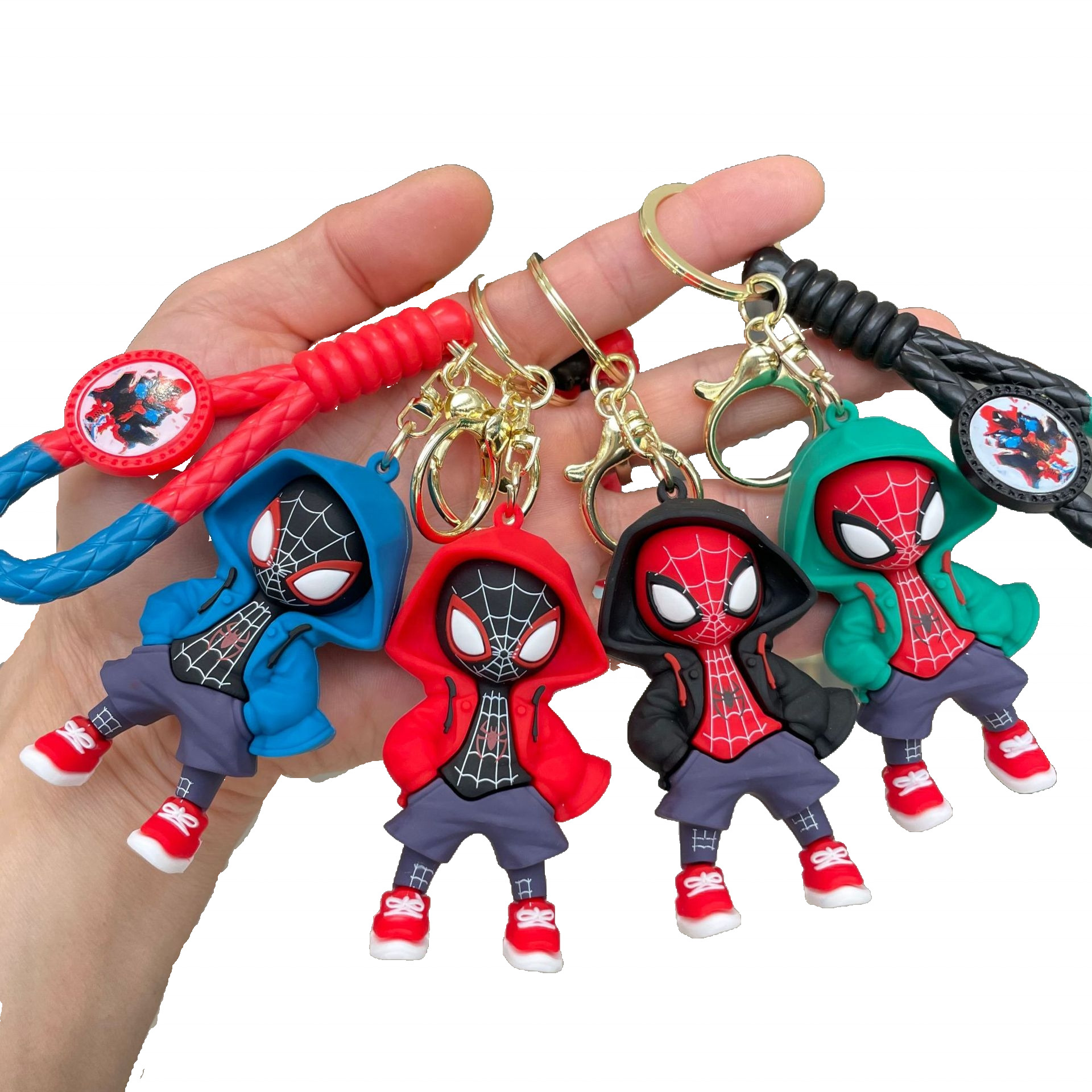 A hand holding a set of four Spiderman Keychains in various colors (blue, red, black, green), all depicting chibi-style Spiderman characters in hoodies, showcasing the range of designs.