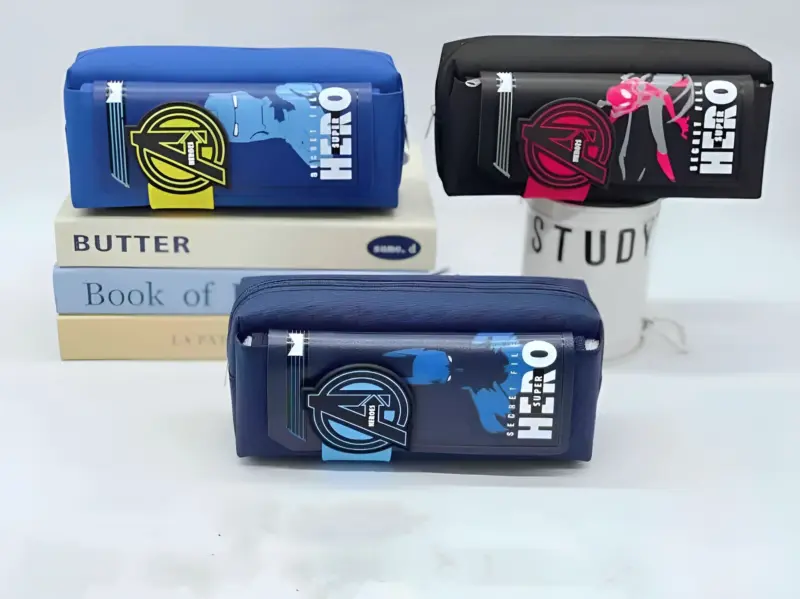 Three Superhero Pouches in blue and black, featuring designs of Captain America, Spider-Man, and an armored hero, stacked on books and a mug, showcasing different character options.