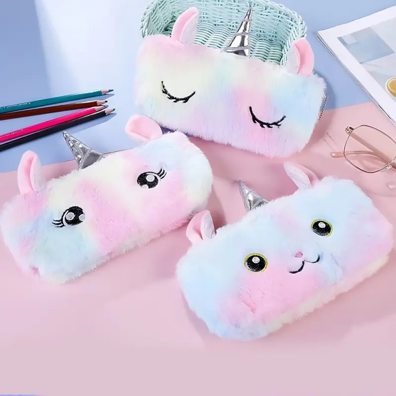 Three fluffy Unicorn Fur Pouches with different facial expressions, arranged on a desk, with one placed inside a woven basket.