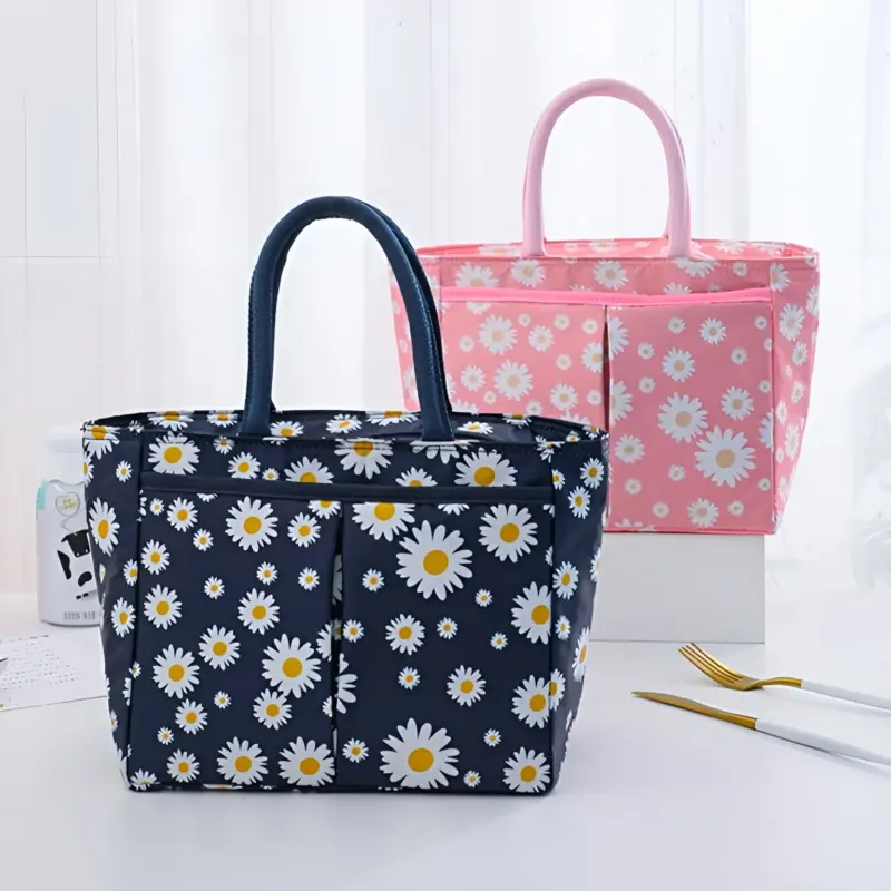A blue Floral Lunch Bag featuring a vibrant pattern of flowers and butterflies on the front, with pink handles and a pink zipper.