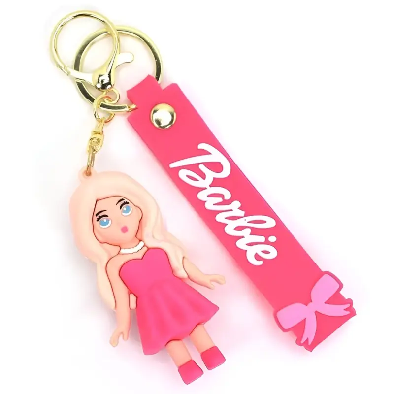 A close-up view of a pink Barbie Doll Keychain with the doll figure in a pink dress and the strap with the Barbie logo, isolated on a white background.