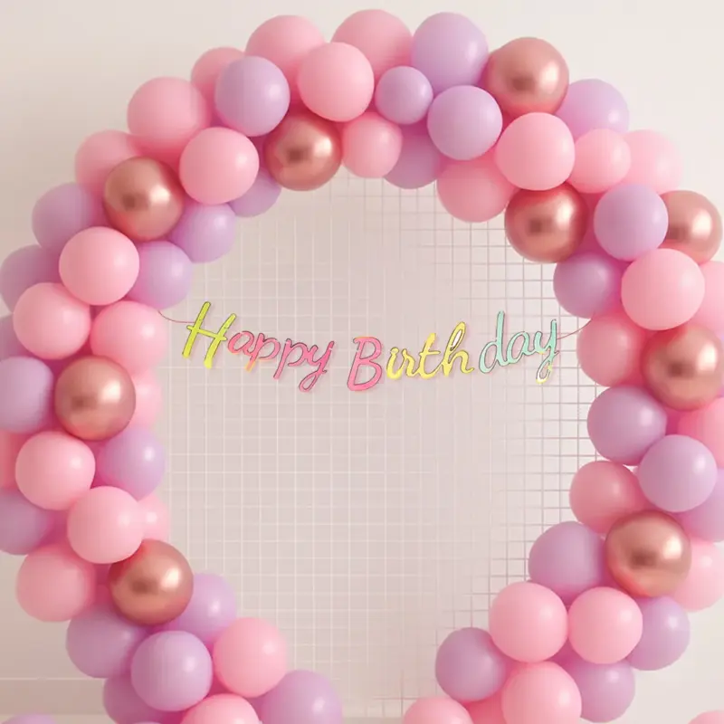 A beautifully arranged balloon arch or garland from a Pink and Lavender Party Kit, featuring pink and lavender pastel balloons, rose gold chrome balloons, and a prominent "Happy Birthday" neon cursive banner.
